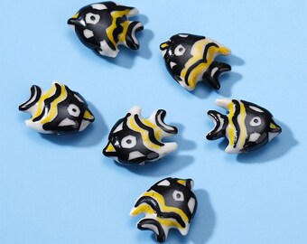 May include: Six black and yellow ceramic fish figurines with white accents. The fish have a wavy pattern and a black eye.