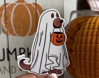 May include: A brown dog dressed as a ghost for Halloween, holding a small orange pumpkin bucket with a jack-o'-lantern face.