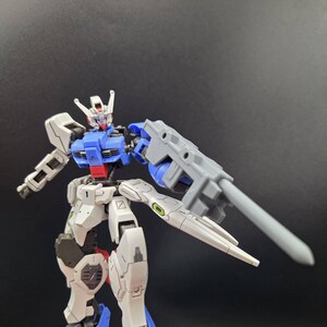 Op de afbeelding: Een beweegbaar robotactiefiguur met een wit, blauw en rood kleurenschema. Het figuur heeft een gedetailleerd mechanisch ontwerp met beweegbare ledematen, een hoofd met een V-vormige kam en een groot grijs wapen aan de linkerarm.