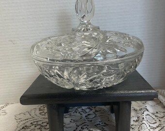 May include: A clear glass candy dish with a lid. The dish has a cut glass design and a knob on the lid.