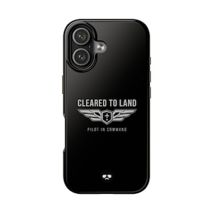 May include: Black phone case with the text "CLEARED TO LAND" above a silver emblem of wings and a plane. The words "PILOT IN COMMAND" are below the emblem. The phone case has a glossy finish.