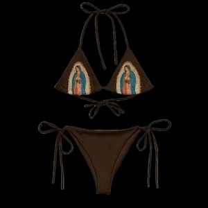 Op de afbeelding: Een bruine bikini met een driehoekige top en een strik-onderkant. De top heeft een geprinte afbeelding van de Maagd Maria.