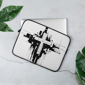 May include: A white laptop sleeve with a black and white abstract cross design. The cross is made up of geometric shapes and lines.
