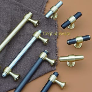 May include: Various cabinet handles and knobs in gold, silver, and black. The handles are long and cylindrical, while the knobs are shorter and cylindrical. The hardware features a brass-coloured base. The brand name "Tinghardware" is visible.