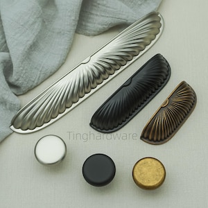 Peut inclure: Diverses poignées et boutons de meubles décoratifs. L'image présente des poignées argentées, noires et en laiton antique, avec un motif en éventail. Les boutons sont ronds. Le texte "Tinghardware" est visible. Idéal pour les projets de rénovation.