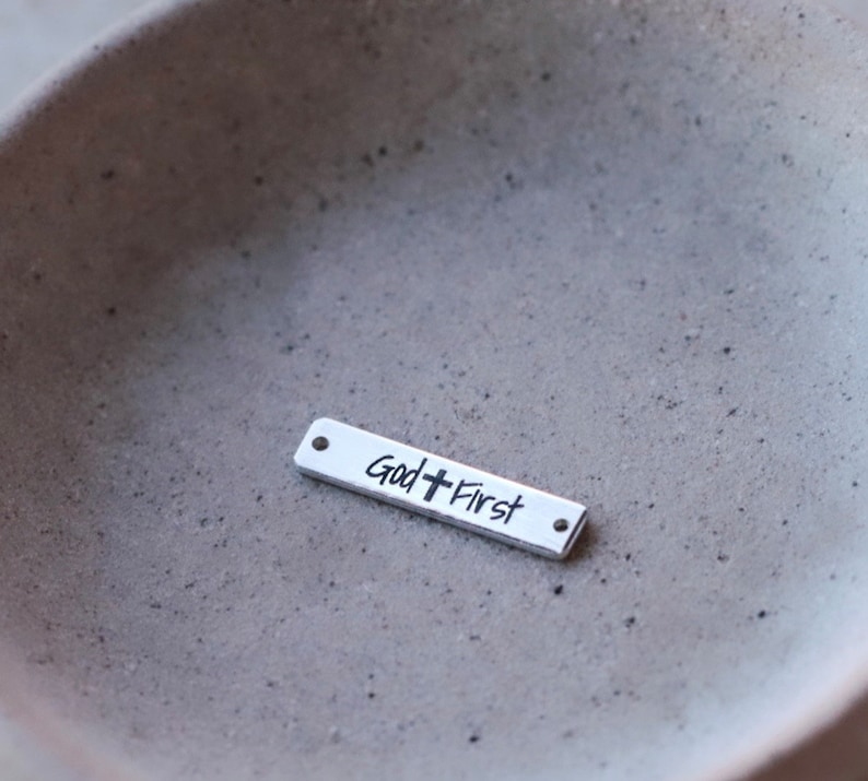 May include: Silver charm with the words "God + First" engraved on it.