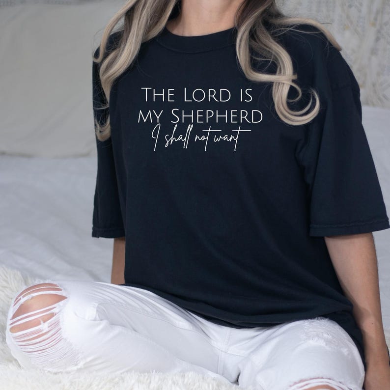 Puede incluir: Una camiseta azul marino con la frase blanca "THE LORD IS MY SHEPHERD I shall not want". La camiseta es de estilo casual y c&oacute;modo.