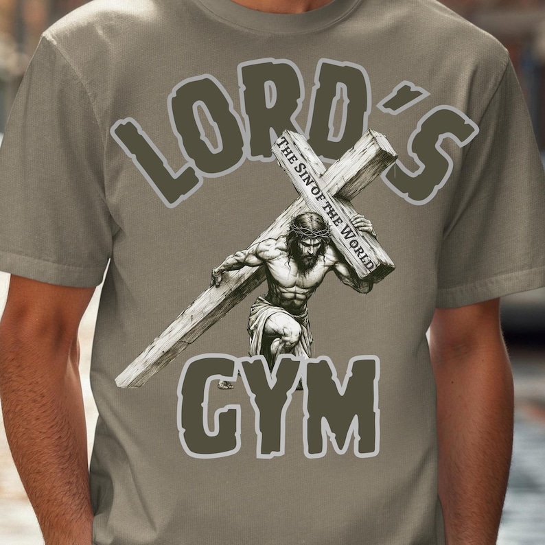 Puede incluir: Camiseta color beige con la frase "LORD'S GYM". El dise&ntilde;o muestra una figura musculosa cargando una cruz, con el texto "The Sin of the World" en la cruz.