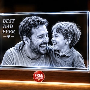 May include: A rectangular glass block featuring a laser-etched black and white photograph of a smiling adult and child. The text BEST DAD EVER is engraved on the left side. The glass sits on a rectangular wooden base with an integrated LED light.