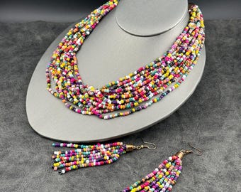 May include: A multi-strand beaded necklace and matching tassel earrings set. The necklace and earrings feature a vibrant mix of colorful beads in shades of pink, yellow, green, and purple. The earrings have gold-colored hooks.