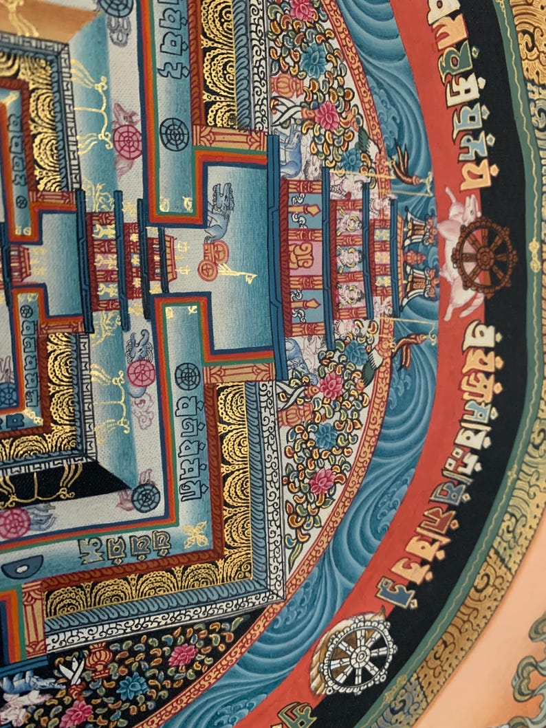 May include: A colorful mandala with intricate details, featuring a central square surrounded by a circular border. The mandala is painted in shades of blue, red, gold, and black, with floral and geometric patterns. The central square contains a smaller mandala with a wheel-like design.