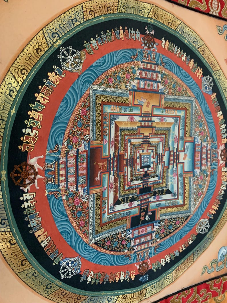May include: A colorful mandala with intricate details and a square pattern in the center. The mandala is surrounded by a circular border with text in a foreign language. The background is a light peach color.