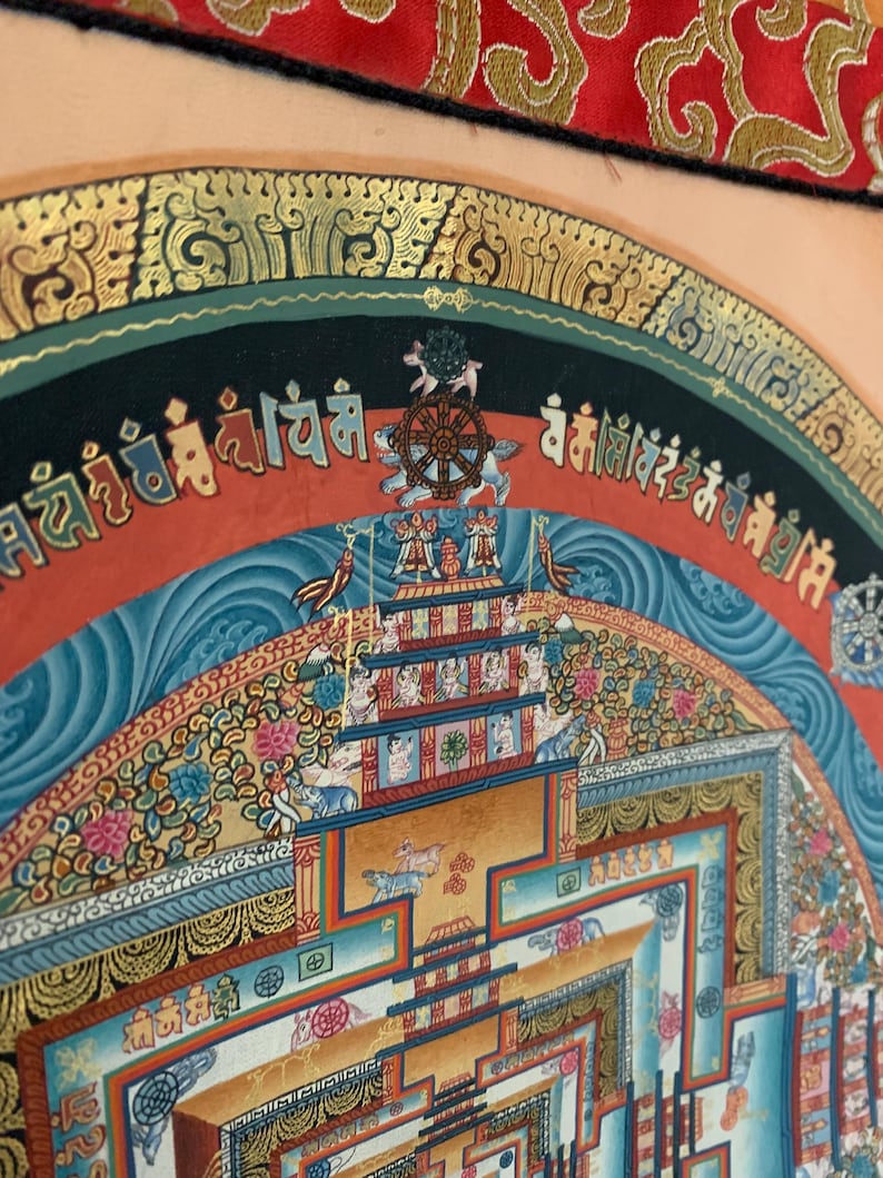 May include: A colorful mandala with intricate details and gold accents. The mandala is surrounded by a border of Tibetan script. The mandala is a symbol of the universe and is often used in meditation.