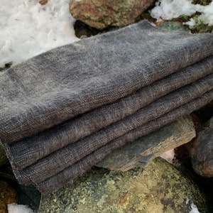 May include: A stack of four gray wool fabric squares, likely for crafting or sewing projects.