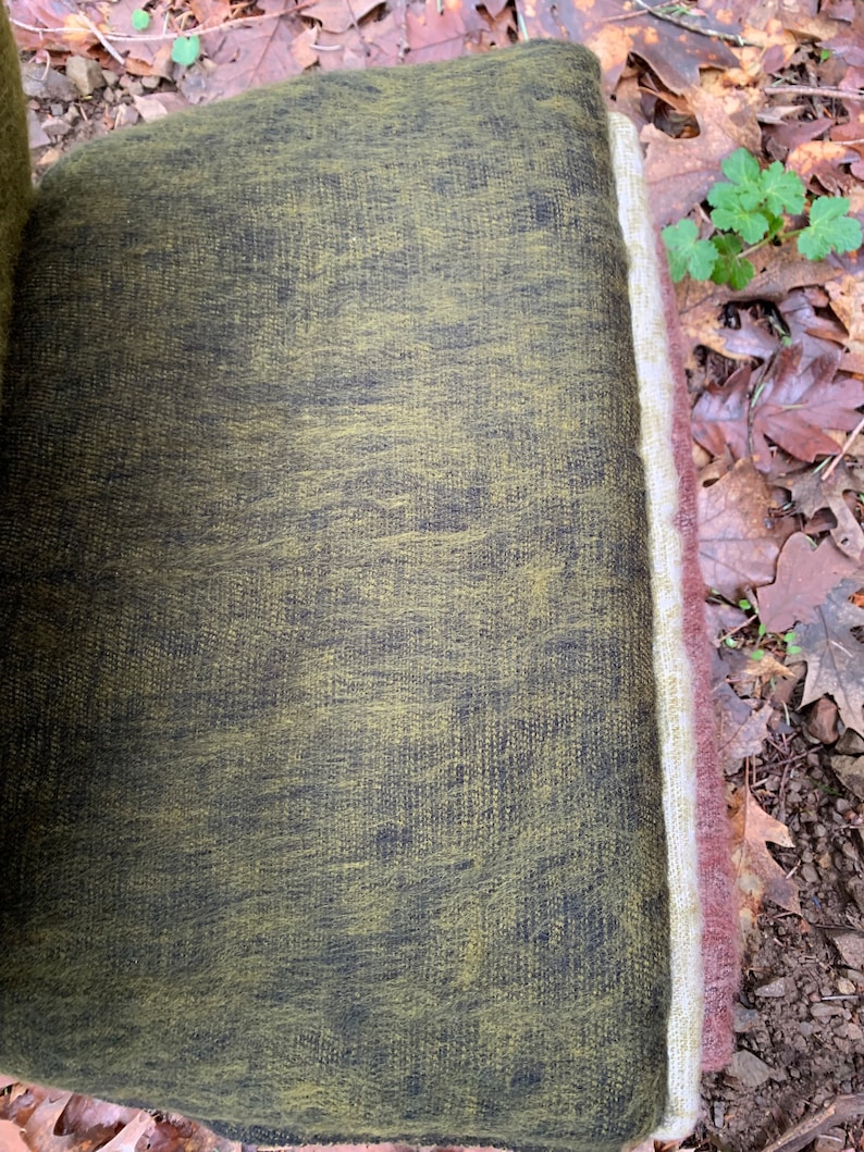 May include: A close-up of a green and black chair cushion with a white and brown border. The cushion is made of a soft, textured fabric.