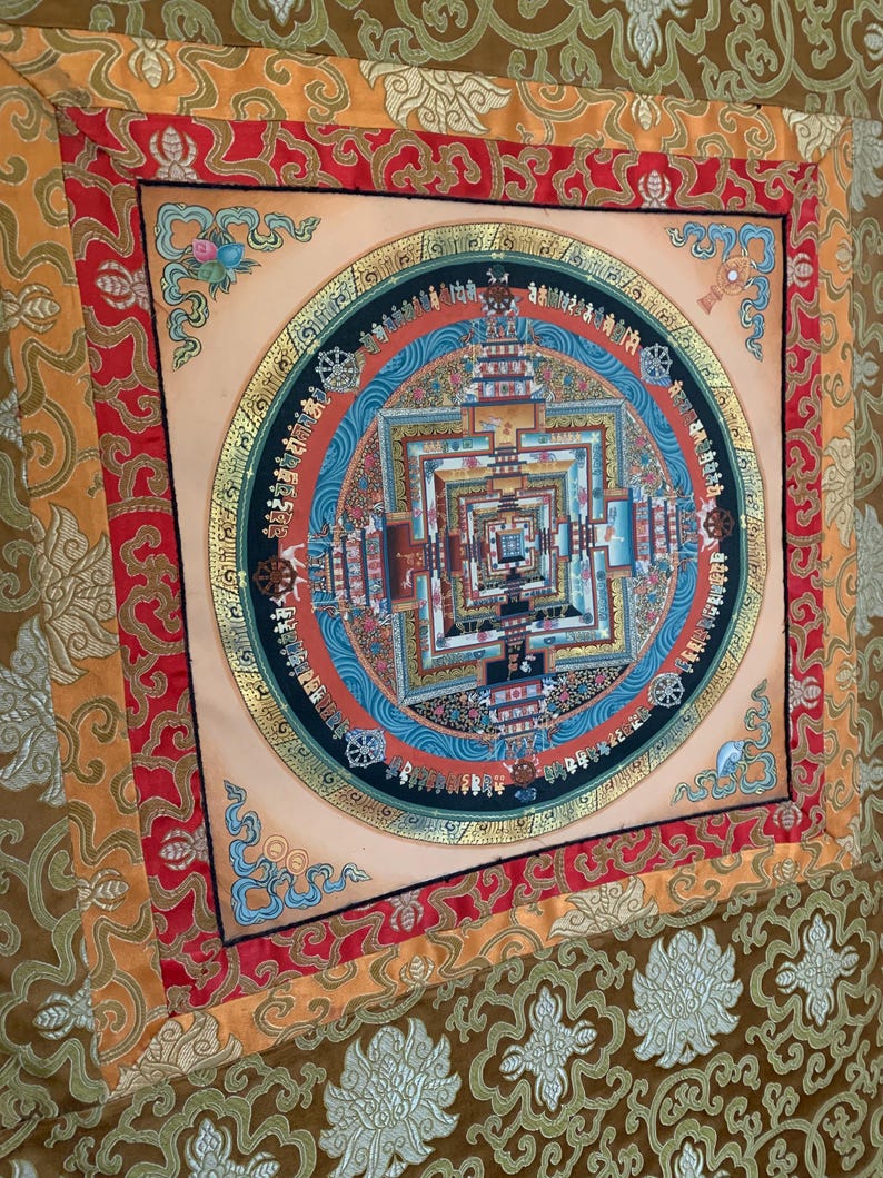 May include: A colorful mandala tapestry with a gold border and intricate details. The mandala is surrounded by a red, orange, and gold border. The tapestry is made of silk and is perfect for adding a touch of spirituality to any room.