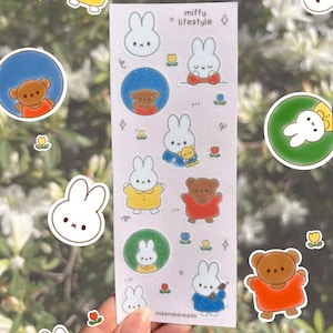 May include: A sheet of stickers featuring illustrations of a bunny rabbit and a bear. The stickers are on a pink background with glitter. The text "miffy lifestyle" is at the top of the sheet. The stickers are perfect for adding a touch of whimsy to your planner, journal, or laptop.