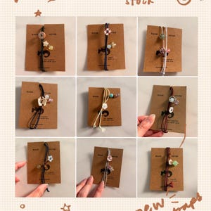 May include: Nine book straps with decorative beads and charms are displayed on brown cards. The straps are in various colors, including black, white, and red. The text "Limited stock" and "new book straps" are visible.