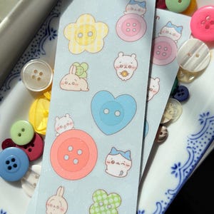 May include: A collection of colorful buttons and stickers with cute illustrations. The stickers feature flower, heart, and button shapes, along with adorable animal characters. The text "chika button" and "miss melonsoda" are visible on the stickers.