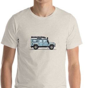 May include: A light blue t-shirt with a graphic of a blue Land Rover Defender with a roof rack.