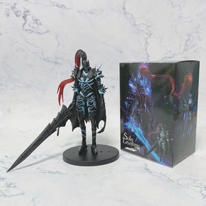 May include: A black and blue action figure of a character with a large sword, cape, and spiky armor, standing on a black base. A matching box with the words "Solo Leveling" is next to the figure.