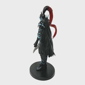 May include: A detailed figurine of a warrior in black armor with blue accents and a flowing black cape. The warrior has a red and black ponytail and is holding a silver blade. The figurine stands on a black circular base.