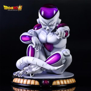 Puede incluir: Estatua blanca y morada de Frieza de Dragon Ball Super. La figura está sentada con los brazos cruzados y señalando. La estatua tiene una cabeza y detalles morados, y está sobre una base redonda con detalles dorados y morados.