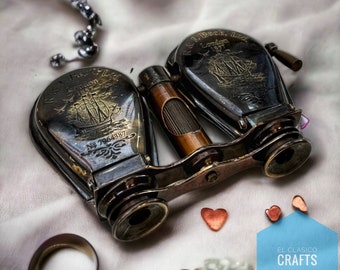 May include: Antique opera glasses with a wooden handle and engraved ship design. The glasses are silver-toned with the text "R & J Beck, Ltd. London 1857" and the serial number "No 7964387". The background includes decorative elements and the text "EL CLASICO CRAFTS".