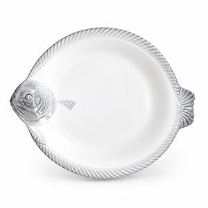 Może przedstawiać: Biały ceramiczny półmisek w kształcie ryby. Talerz posiada szczegółowo odwzorowaną głowę ryby po lewej stronie oraz teksturowaną płetwę ogonową po prawej. Krawędź półmiska ozdobiona jest ciągłym, wypukłym wzorem przypominającym skręcony sznur.