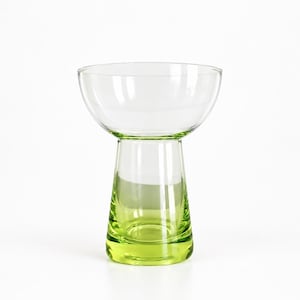Peut inclure: Un récipient en verre transparent doté d'une partie supérieure large en forme de bol qui se transforme en une base cylindrique effilée. La partie inférieure du verre est teintée d'un vert citron vif qui s'estompe vers le haut en verre clair.