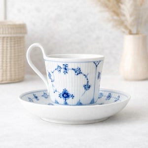 Può includere: Servizio da tè in porcellana bianca con motivi floreali blu. La tazza ha un manico curvo e una texture a coste verticali. Il piattino rispecchia il design della tazza, creando un'estetica classica ed elegante. Per tè o caffè.