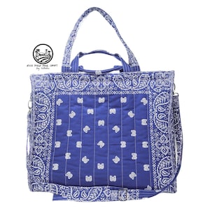 May include: A blue tote bag with a white paisley pattern and a matching shoulder strap. The bag has a top handle and a rectangular shape. The bag has the text "RICE FIELD FOLK CRAFT bag collection" and a logo.