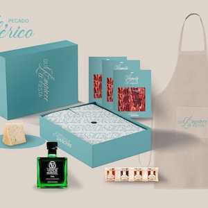 May include: A gift box set featuring a blue box with the text "Que Empiece La Fiesta" and the words "Pecado Iberico" in a decorative script. The set includes a box of cured ham, a bottle of olive oil, a block of cheese, and a set of small bottles. The set also includes a beige apron with the same text as the box.