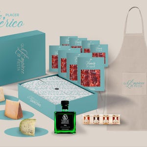 May include: A gift set featuring a blue box with the text "El Empiece La Fiesta" and the words "Placer Iberico" above it. The box contains a variety of cured meats, cheese, and a bottle of olive oil. The set also includes a white apron with the same text as the box.