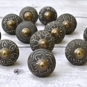 以下が含まれることがあります： 複雑な白いデザインと金のアクセントが施された、黒いセラミック製の引き出しノブ12個のセット。ノブには、花柄、幾何学模様、抽象的なデザインなど、さまざまなパターンがあります。