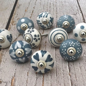 以下が含まれることがあります： 青と白のさまざまなパターンでできたセラミックノブが10個。ノブは丸型で、銀色の金属ベースが付いています。