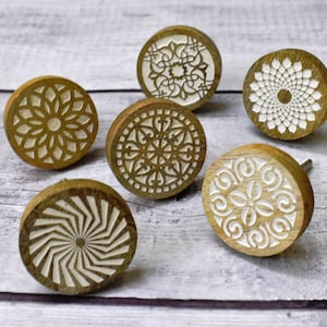 Op de afbeelding: Zes houten knoppen met ingewikkelde witte ontwerpen die in het oppervlak zijn gegraveerd. De knoppen zijn rond en hebben een natuurlijke houten afwerking.