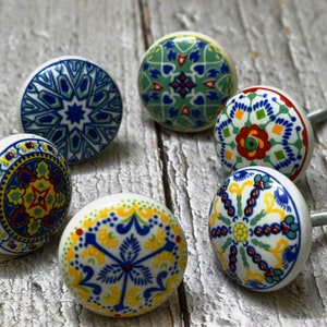 Puede incluir: Seis pomos de cajón de cerámica con intrincados patrones coloridos. Los pomos son redondos y tienen una base blanca con acentos azules, verdes, amarillos y rojos. Son perfectos para agregar un toque de estilo bohemio a cualquier habitación.