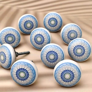 Op de afbeelding: Tien keramische kastknoppen met een blauw en wit mandala-ontwerp. De knoppen hebben een zilveren schroef om aan een kastdeur te bevestigen.