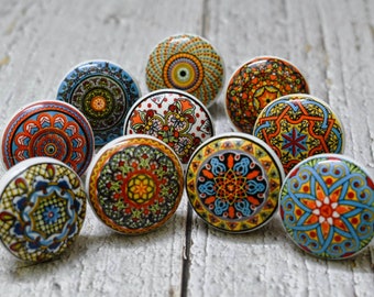 Puede incluir: Surtido de diez pomos de armario de cerámica con diseños de mandala coloridos e intrincados. Los pomos son redondos y tienen una base blanca con una variedad de colores, incluidos el azul, el rojo, el amarillo, el naranja y el verde.