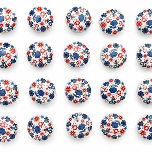 Op de afbeelding: Een verzameling van eenentwintig witte keramische kastknoppen. Elke knop is rond en versierd met een patroon van blauwe en rode bloemen en bladeren. De knoppen zijn gerangschikt in een rasterpatroon tegen een witte achtergrond.