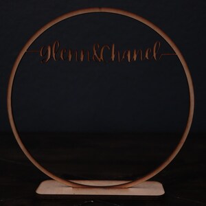 May include: A wooden circle with the words "Glenn & Chanel" cut out, standing on a wooden base.