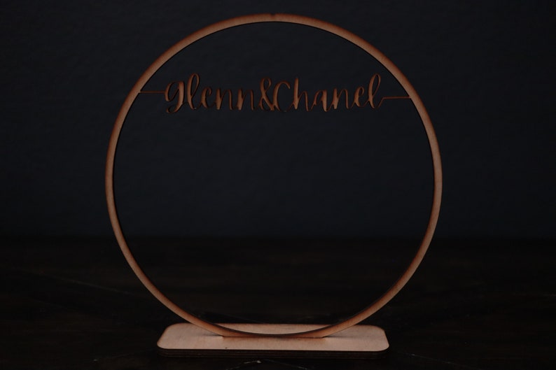 May include: A wooden circle with the words "Glenn & Chanel" cut out, standing on a wooden base.