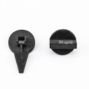 Puede incluir: Dos objetos negros impresos en 3D. Uno es de forma circular con una barra rectangular y el texto "3DLogoGZ". El otro es un objeto negro en forma de alfiler con un agujero cuadrado. Ambos objetos están sobre un fondo blanco.