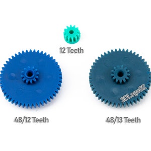 May include: Three plastic gears in blue, teal, and green are shown against a white backdrop. The gears vary in size, with text indicating the number of teeth: 48/12 Teeth, 48/13 Teeth, and 12 Teeth. The image is suitable for engineering or mechanical projects.