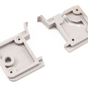 May include: Two gray 3D printed plastic parts for a 3D printer. The parts are designed to hold a spool of filament.
