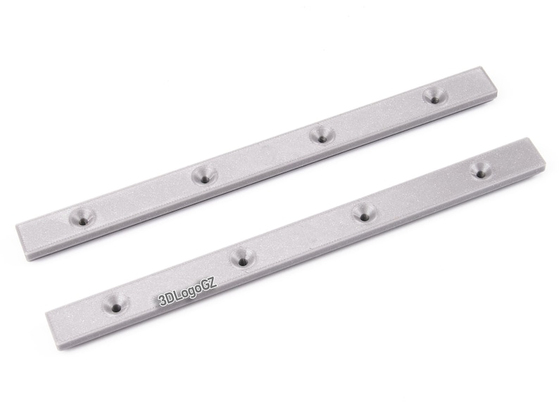 Pode incluir: Duas tiras de metal prateadas, retangulares com bordas arredondadas, cada uma com cinco orif&iacute;cios embutidos espa&ccedil;ados uniformemente. As tiras est&atilde;o dispostas diagonalmente sobre um fundo branco. O texto "3DLogoGZ" &eacute; vis&iacute;vel em uma tira.