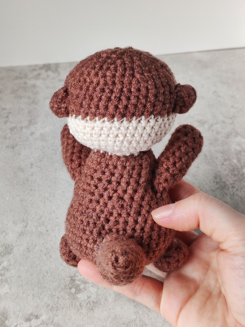 May include: A brown crocheted otter soft toy with a white crocheted tummy.