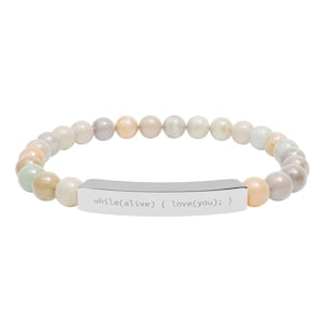 May include: Beaded bracelet with a mix of pastel-colored round beads. A silver-colored rectangular bar in the center is engraved with the text "while(alive) { love(you); }". The bracelet is on a white background.