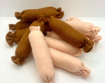 May include: A group of felt sausages in brown and pink colors. The sausages are arranged in a pile, with the brown sausages on the bottom and the pink sausages on top.